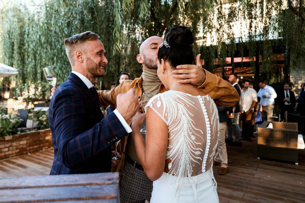 Wedding guests embracing and celebrating at an outdoor reception under trees.