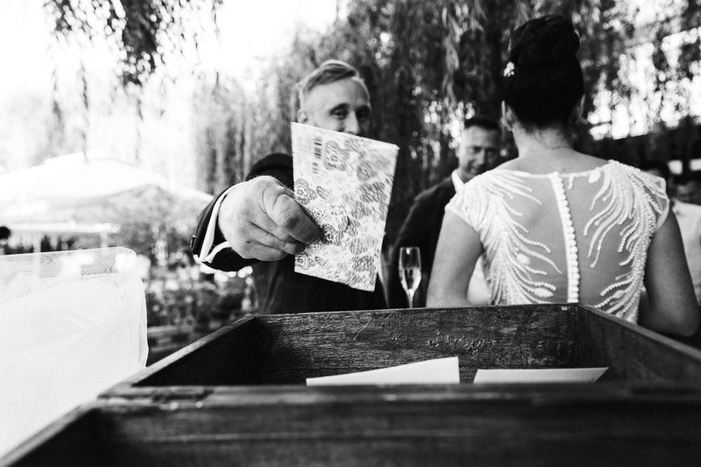 Black and white photo of guests at an outdoor wedding reception signing a guest book.