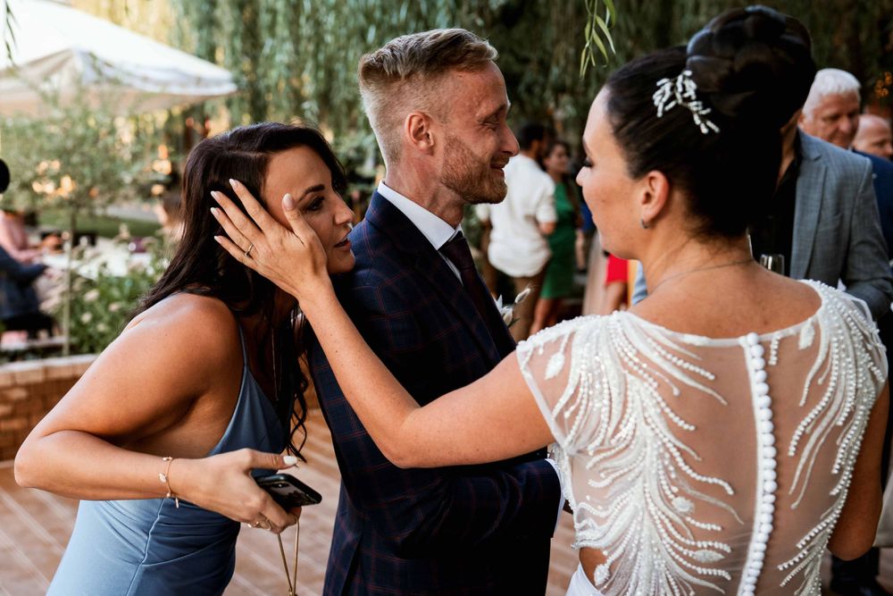 Wedding guests share emotional moments and embraces during outdoor celebration.