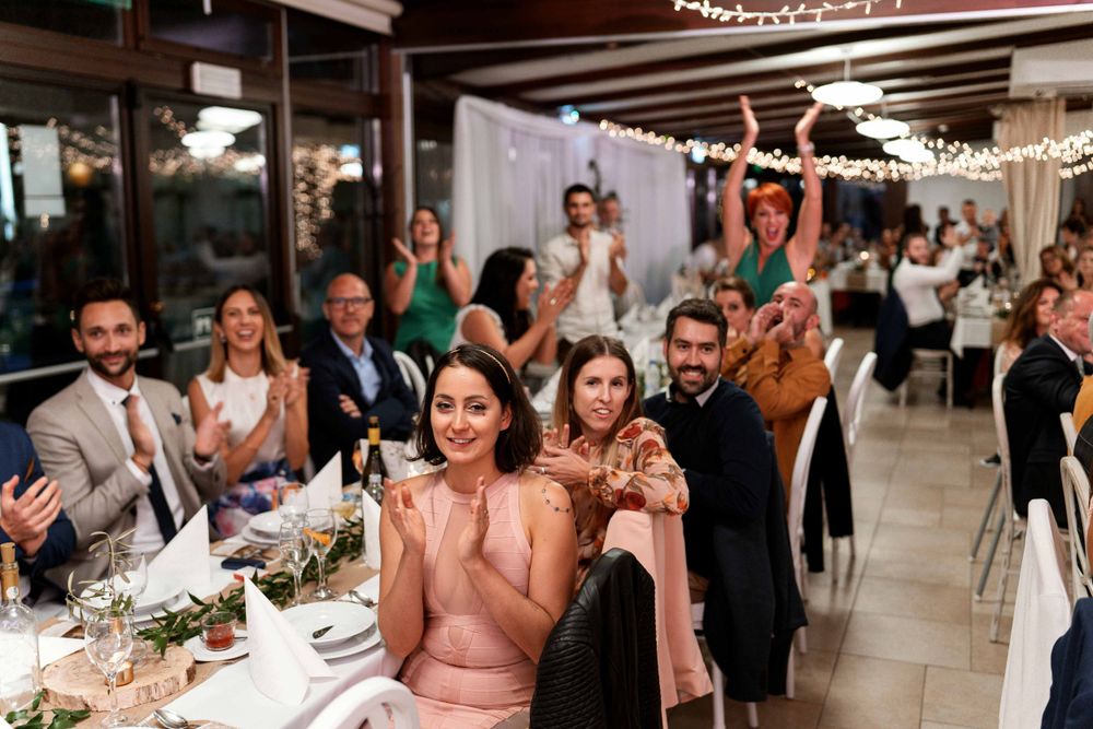 Wedding reception guests celebrate enthusiastically at decorated indoor venue.