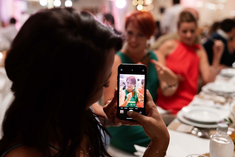 Someone taking a photo of a vibrant display on their phone during a formal dinner event.