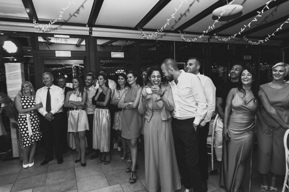 Black and white photo of wedding guests lined up watching a performance at a reception.