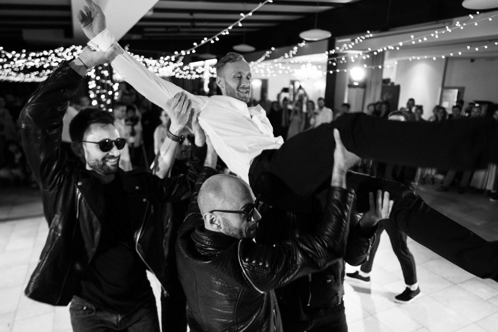 Three people execute a dramatic lift move during a reception celebration.