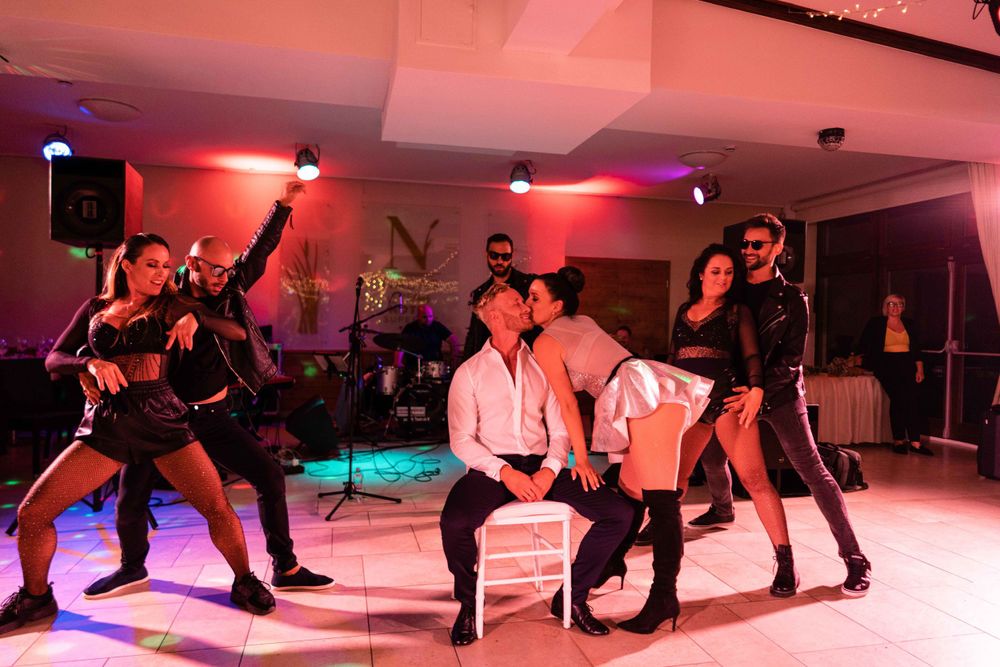 Dancers perform a choreographed routine under red lighting at a wedding reception.