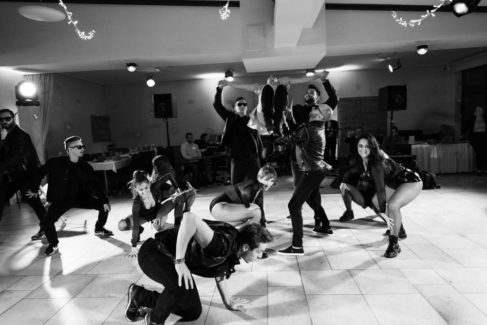 Black and white photo of dancers performing a synchronized dance routine in a studio space with spotlights.