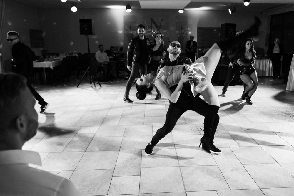 Dancers performing dynamic dance moves in a black and white photograph on a dance floor.