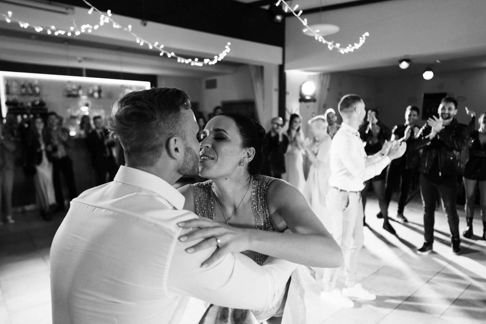 Wedding dancers embracing on an illuminated dance floor with string lights overhead.