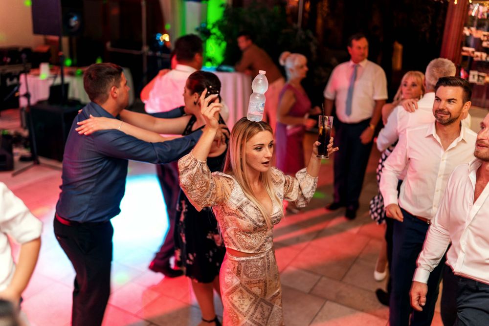 Guests dancing and celebrating at a lively party with colorful lighting effects.