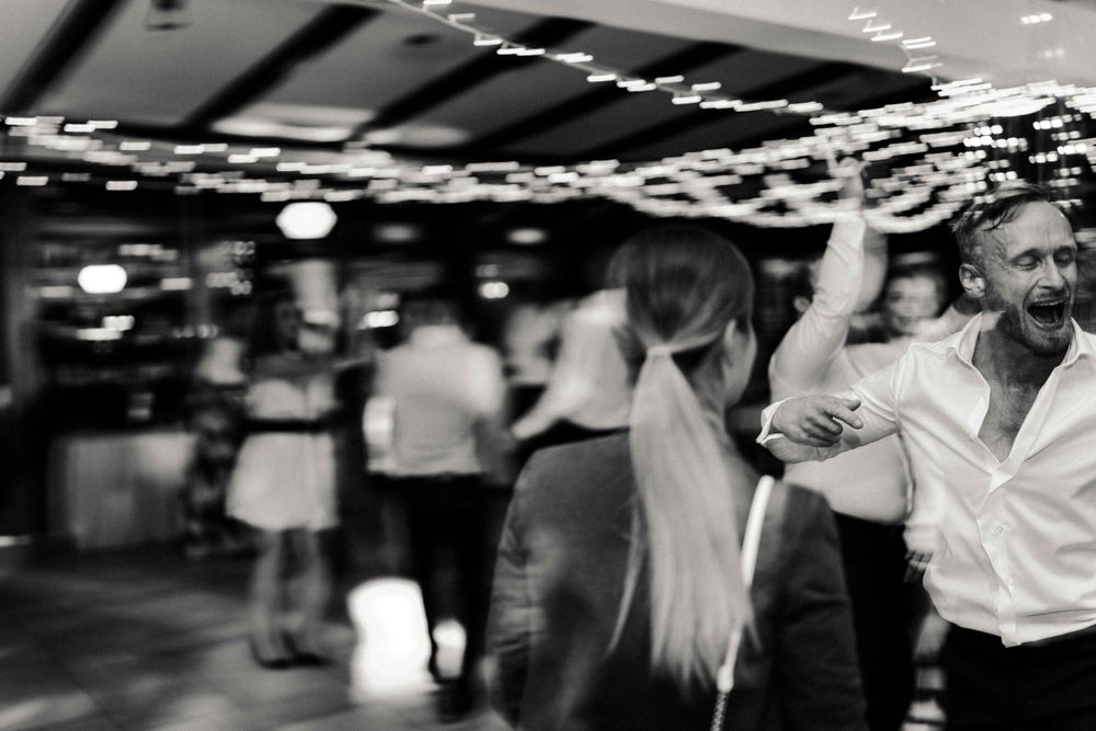People dancing in a dimly lit venue with string lights decorating the ceiling.