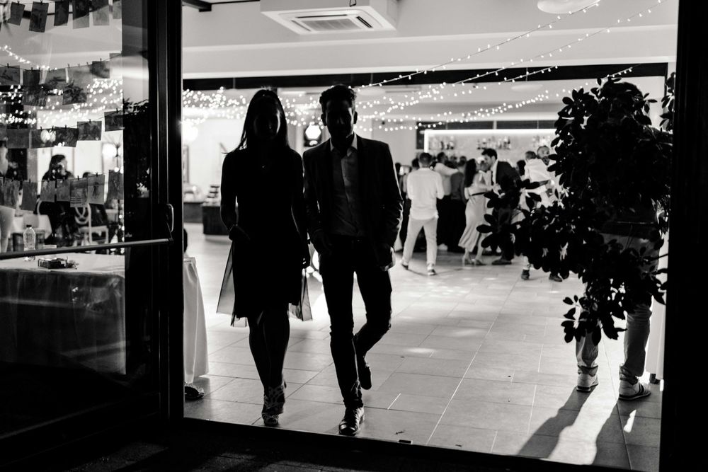 Silhouettes walking through a bright doorway in a black and white photograph.
