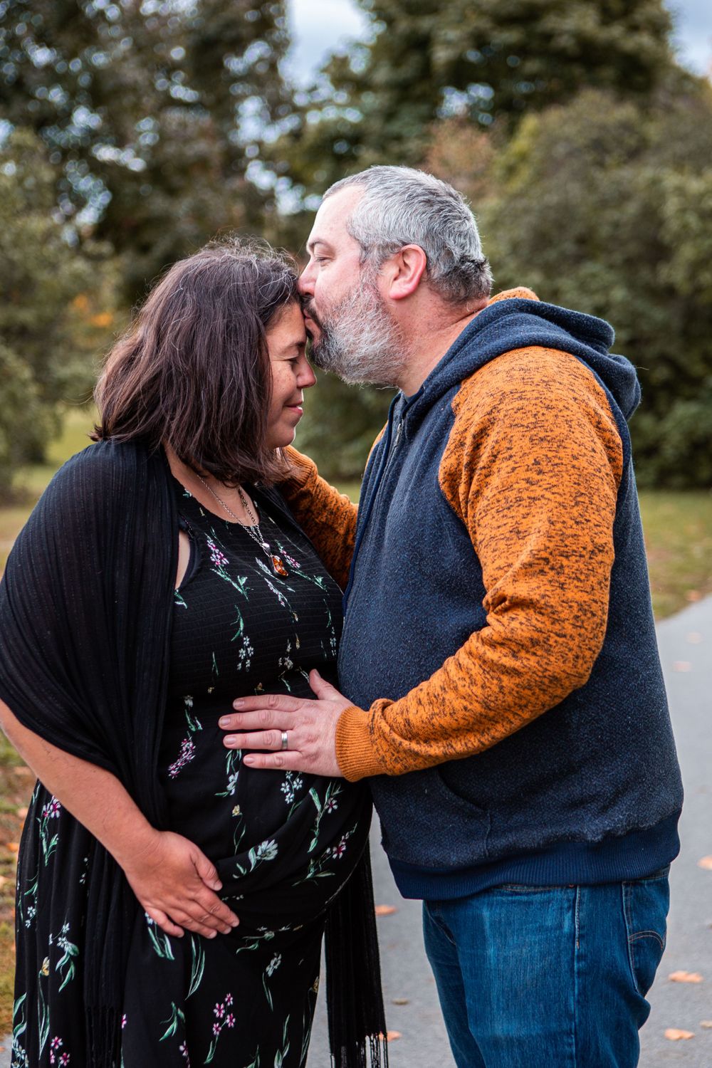 Fall outdoor photoshoot with couple sharing intimate moment on path with autumn leaves.