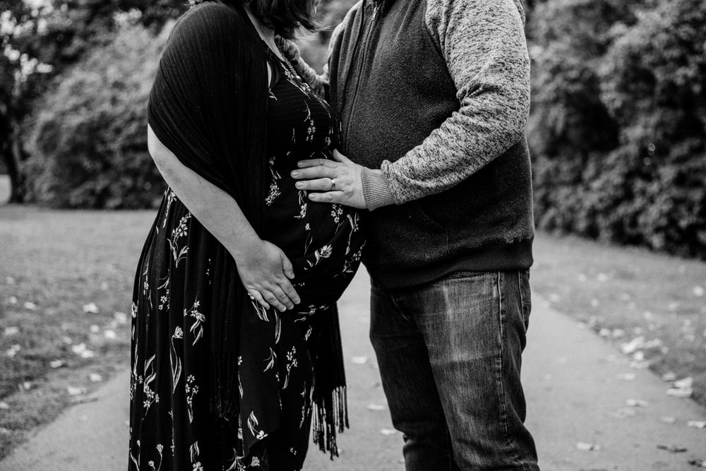 Couple shares tender moment during outdoor autumn photoshoot on walking path.
