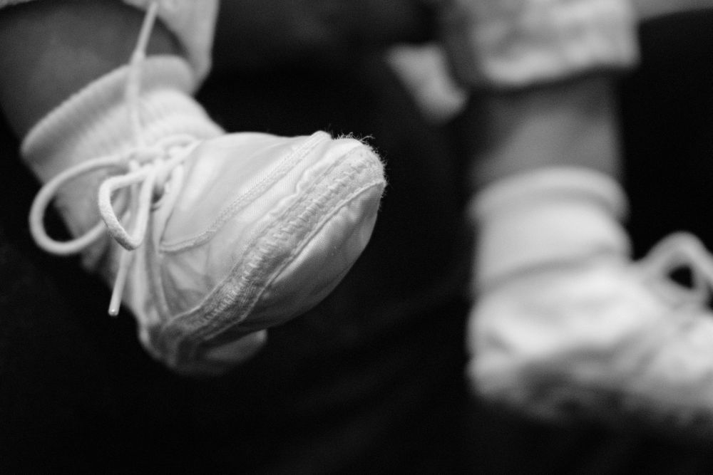 Close-up black and white photo of a baby's white christening shoe.