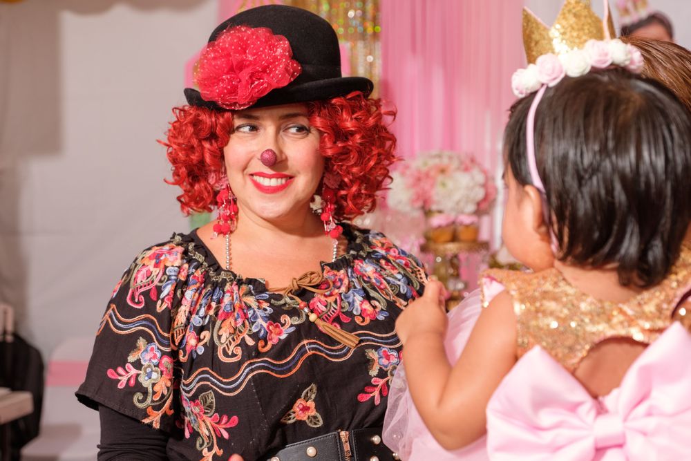 Performer in red curly wig and black dress at party event.
