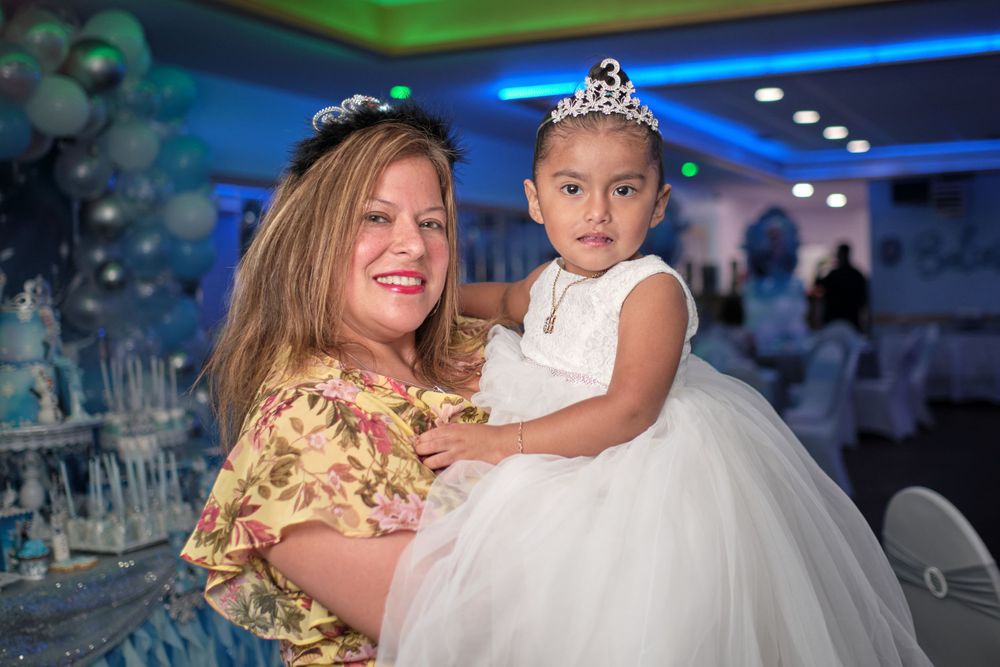 A celebration features an elegant white formal dress and tiara at a decorated indoor venue.