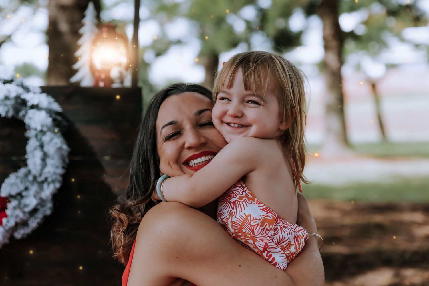 A joyful outdoor summer portrait showing warm embraces and smiles against a natural background.