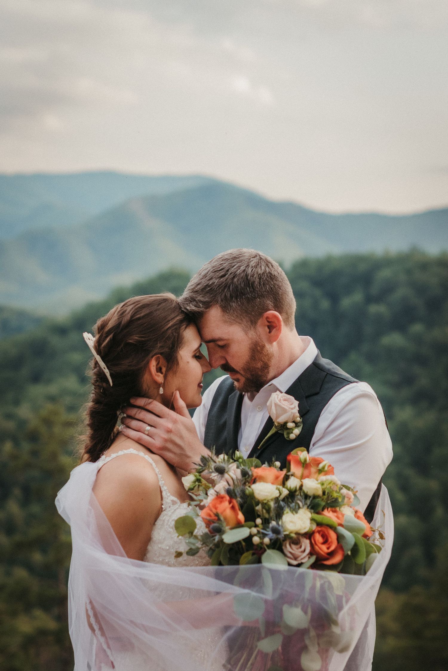 A romantic mountain wedding portrait with colorful bouquet against scenic backdrop.