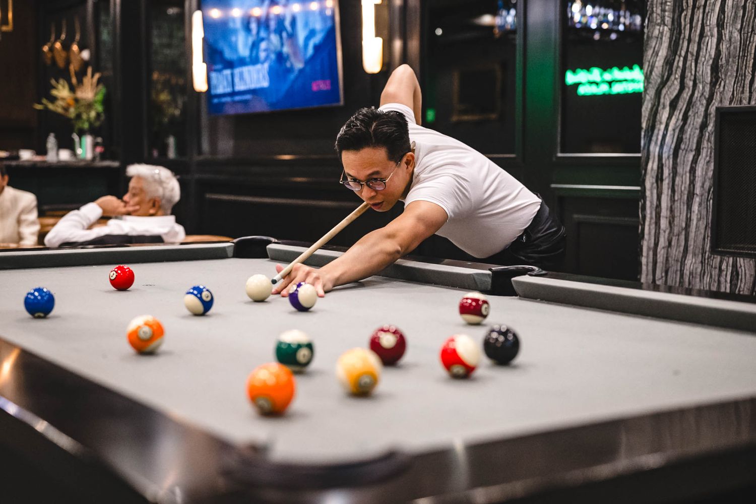 Pool table with colorful billiard balls in an entertainment venue with blue lighting.