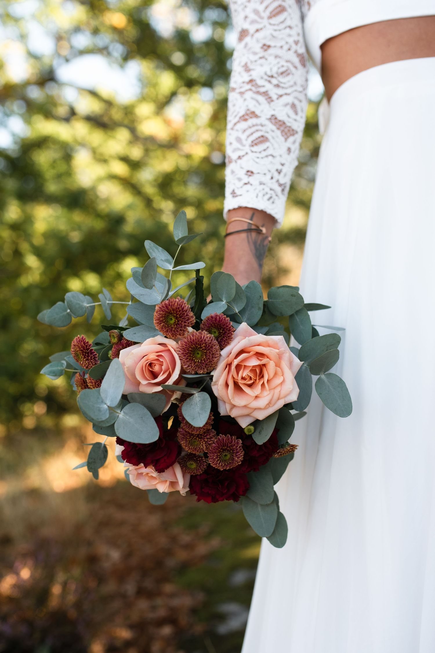 Modern bridal bouquet featuring roses and eucalyptus against white wedding dress.