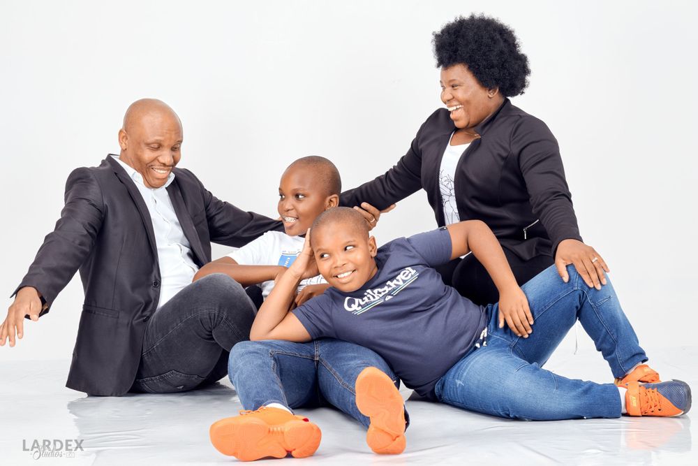 Candid family portrait showing playful interaction on white background.
