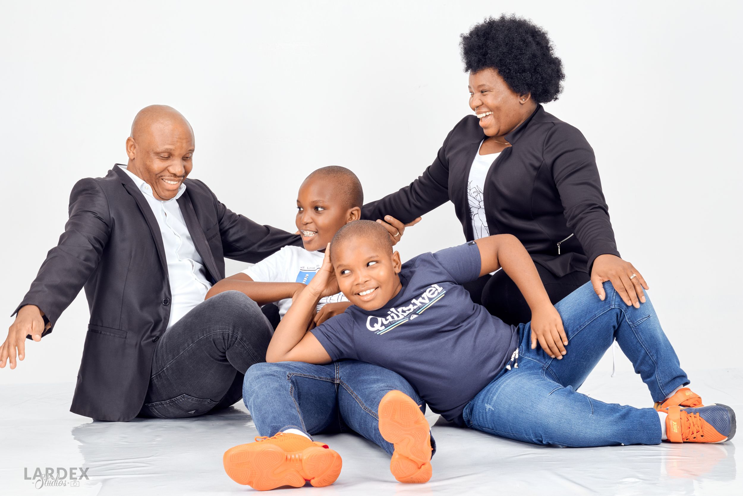 Candid family portrait showing playful interaction on white background.