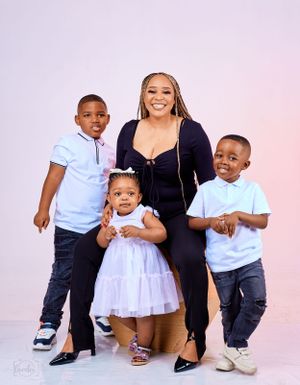 Group portrait in coordinating white and navy outfits against a light pink background.