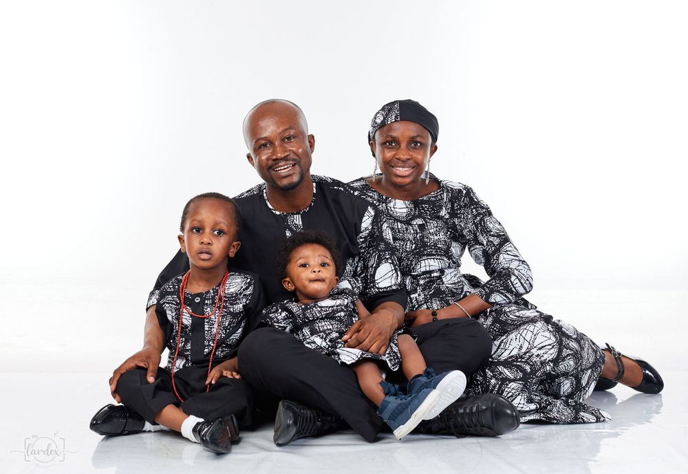Family portrait with matching black and white patterned outfits against white background.