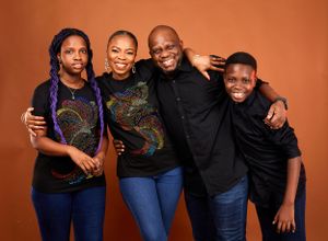 Candid family portrait with everyone wearing black tops and sharing genuine smiles.