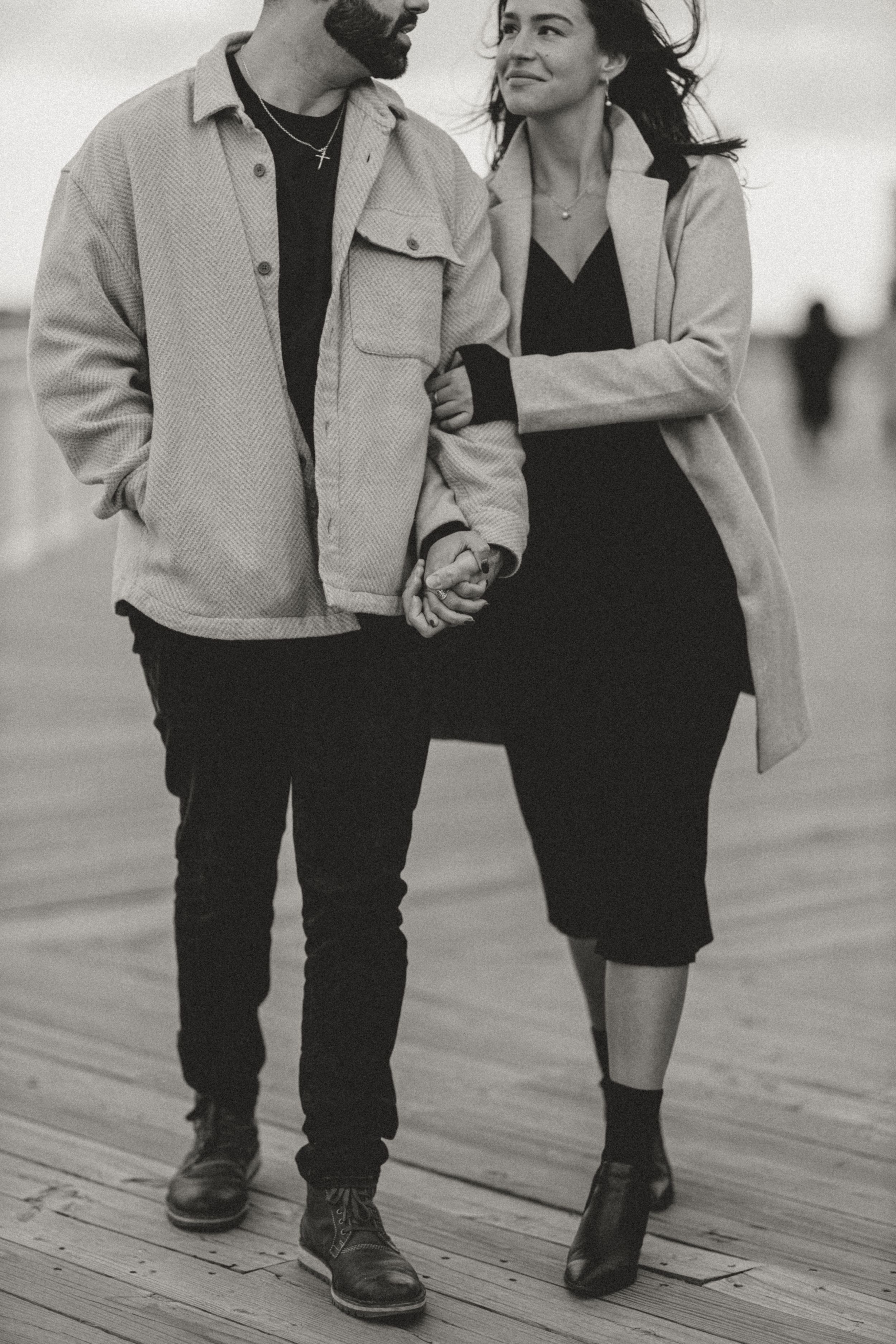 Intimate black and white portrait of a couple walking together on a wooden deck.