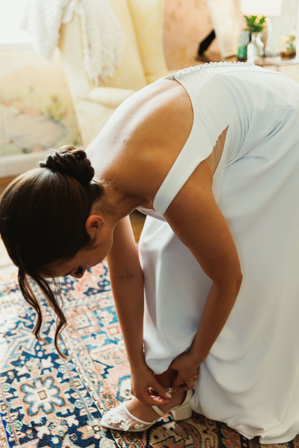 Wedding preparation scene showing dress adjustments on a decorative blue and white patterned rug.