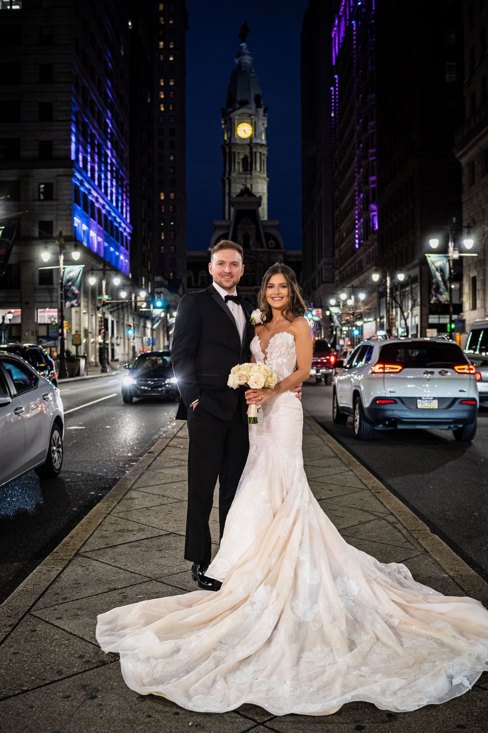 An elegant wedding portrait on Broad Street with Philadelphia's historic City Hall and traffic lights creating ambiance.