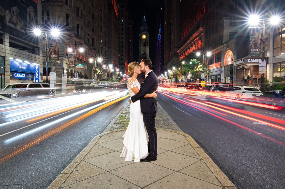 A wedding portrait on Broad Street with colorful light trails from passing traffic creating a dynamic urban scene.