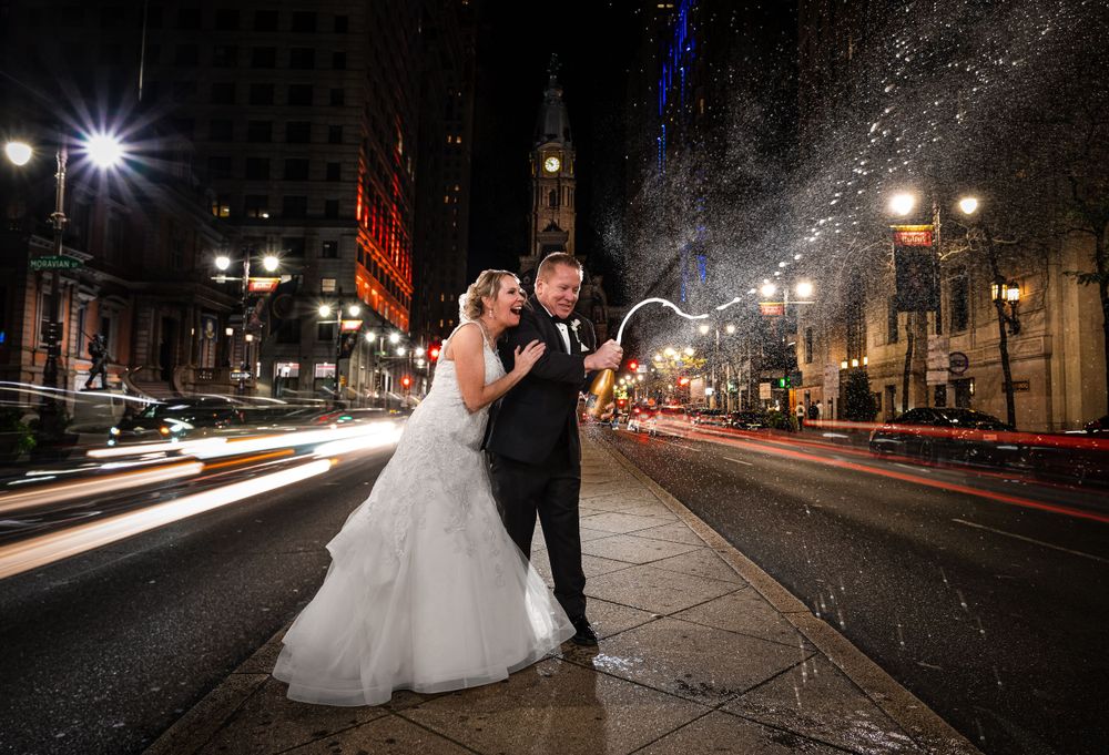 A nighttime wedding photo with light trails from passing cars on Philadelphia's Broad Street.