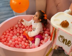 Party setup with decorative balloons and large pink ball pit installation.