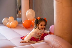 Peach-colored ball pit with white and orange balloon decorations for celebration.