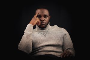 Person in light colored sweater photographed in dramatic low key lighting.