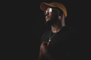 Stylish portrait of person wearing brown cap and sunglasses in low light setting.