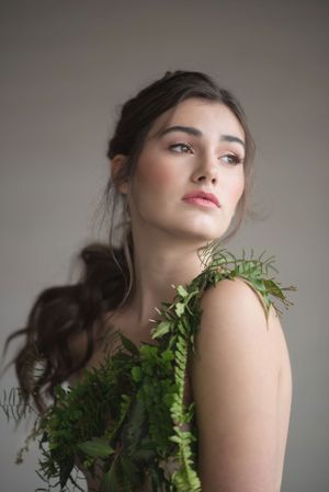Ethereal beauty portrait with delicate ferns adorning the shoulder against a neutral backdrop at Sanctuary Gardens, Kelowna B.C.