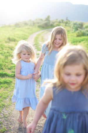 Children in blue dresses walk along sunny mountain path in Kelowna, B.C.