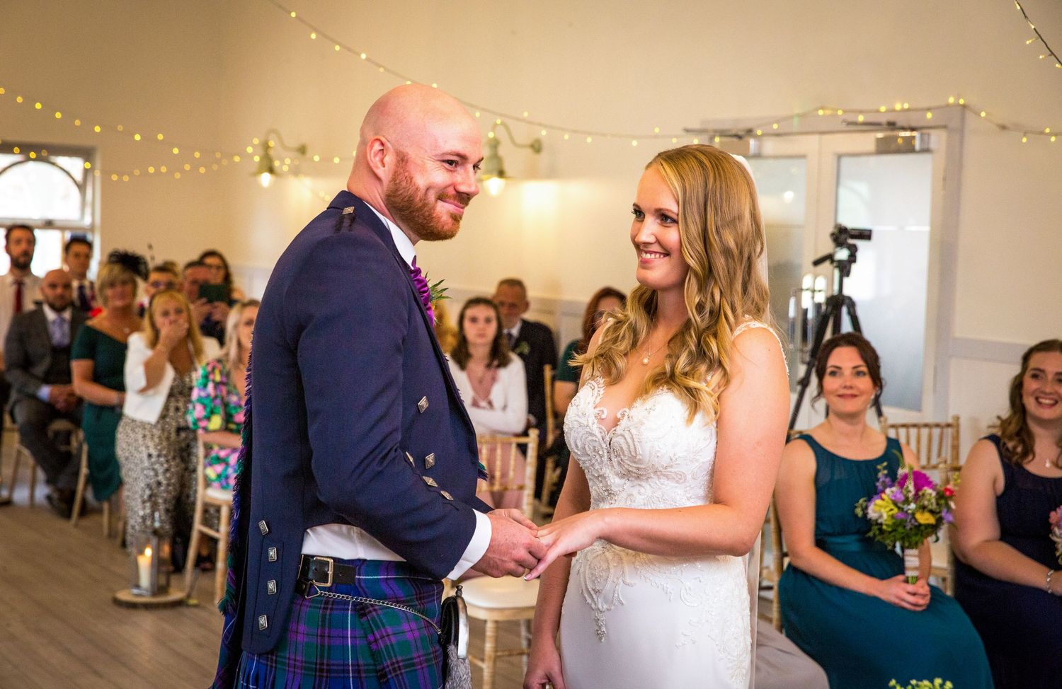 Wedding celebration with fairy lights and guests dancing in an indoor venue.