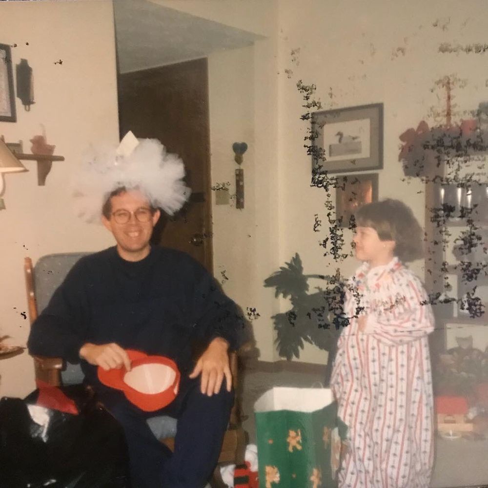 A vintage holiday photo showing people in a living room with Christmas decorations.