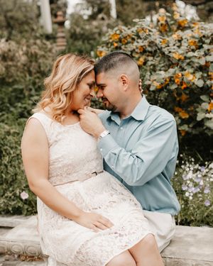 Romantic couple sharing an intimate moment in a garden with white flowers and orange blooms in the background.