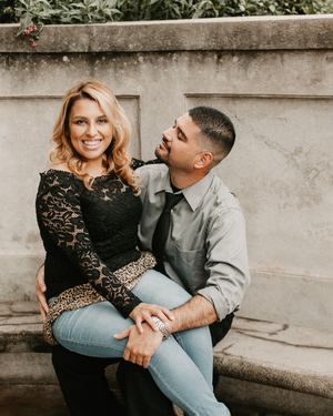 Couple sitting together on stone steps sharing a playful moment in casual attire.