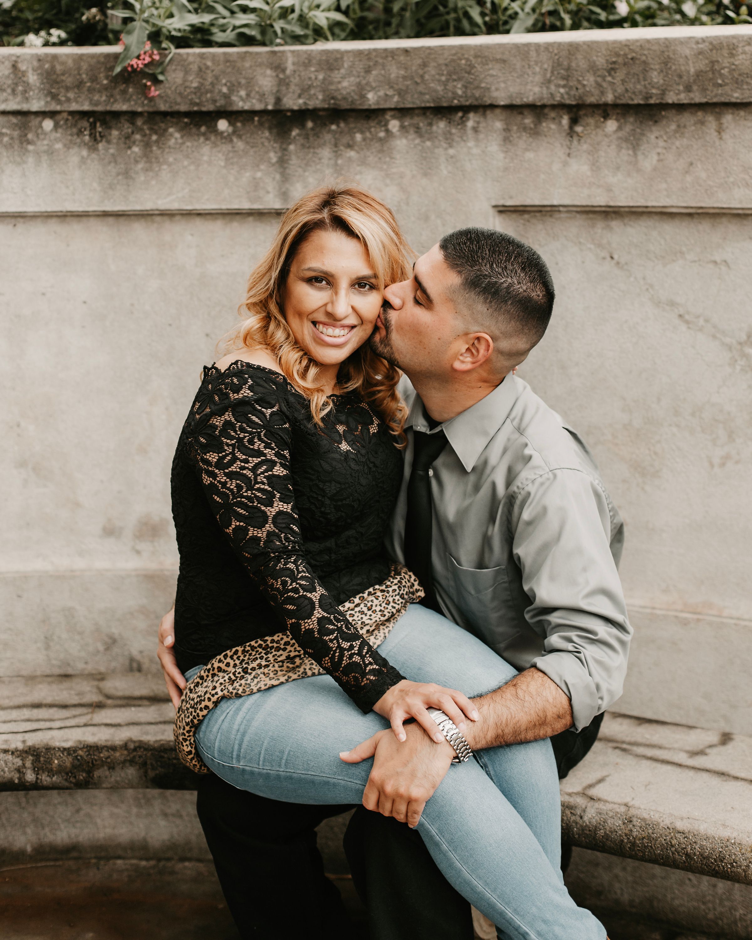 Affectionate couple embracing on stone steps, wearing casual clothing with lace and denim.