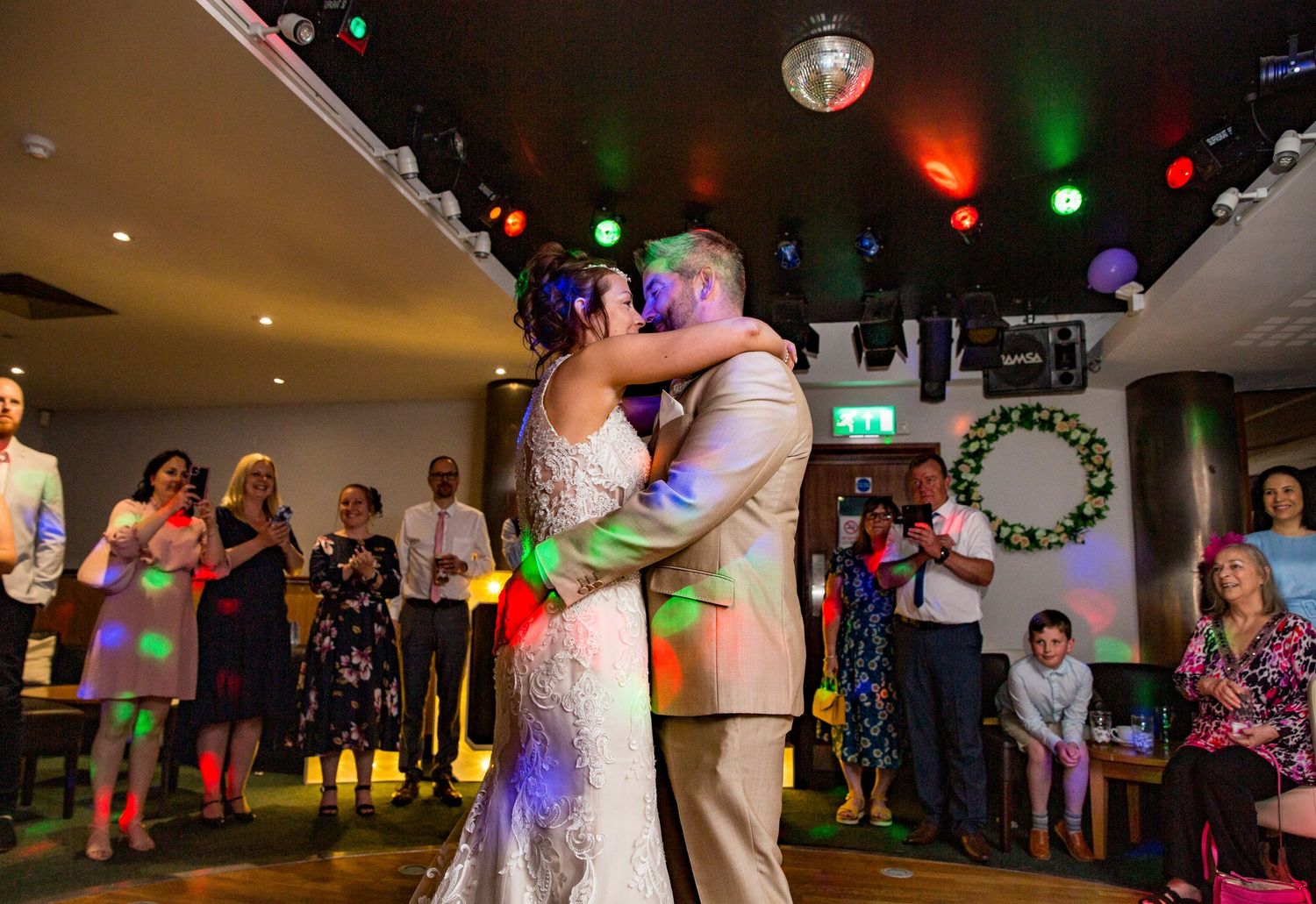 Wedding reception dance floor scene with disco lights and couples dancing.