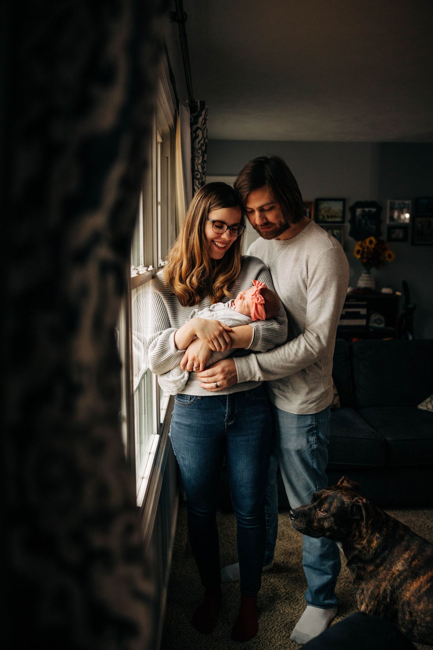 A couple embraces their newborn baby girl in their home Captured By Grace Photography Traverse City Michigan