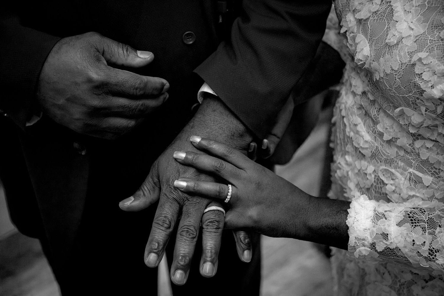 Close-up of hands with wedding rings in black and white photography.