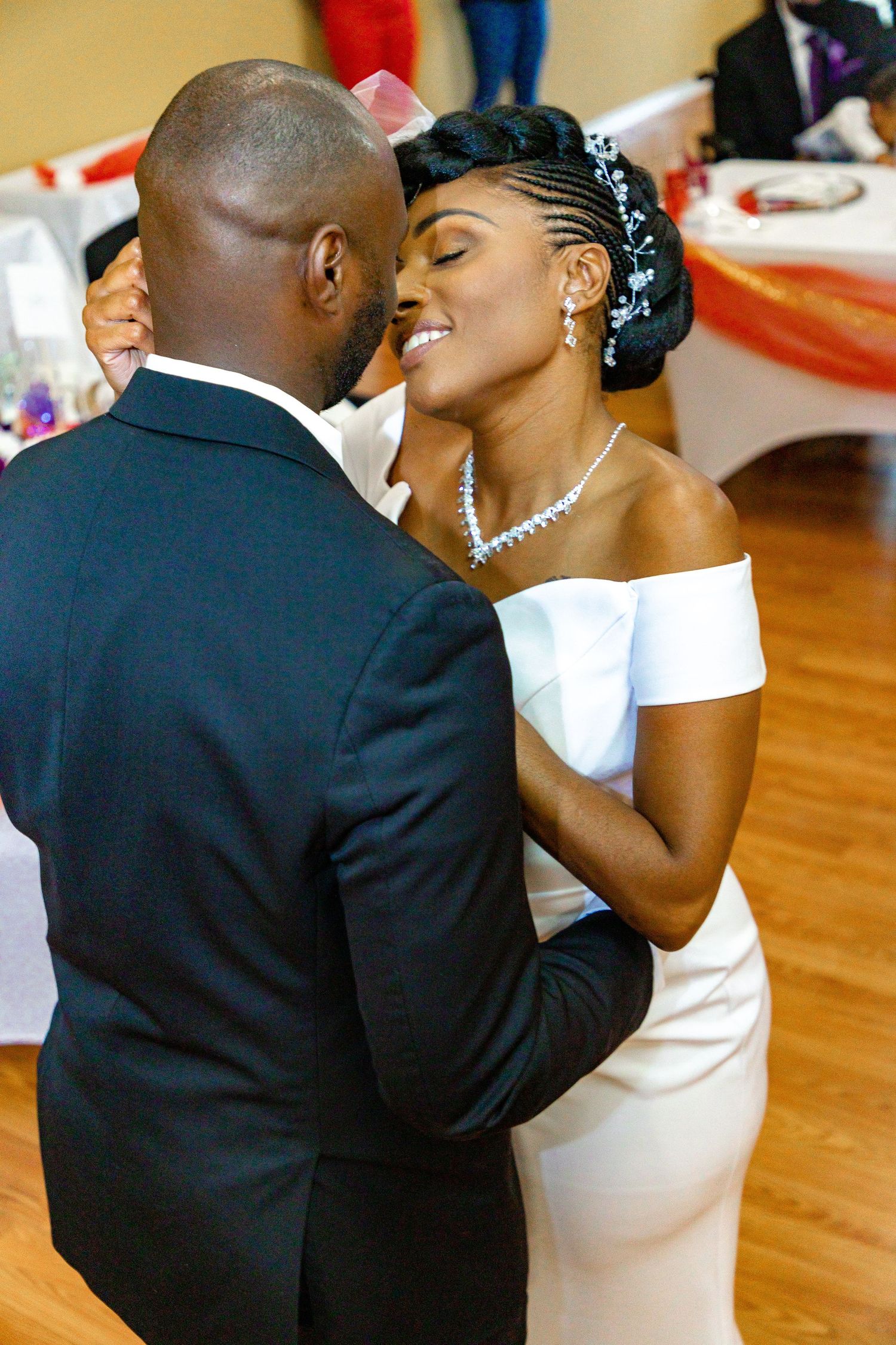 A romantic moment between newlyweds dancing in formal attire at their reception.