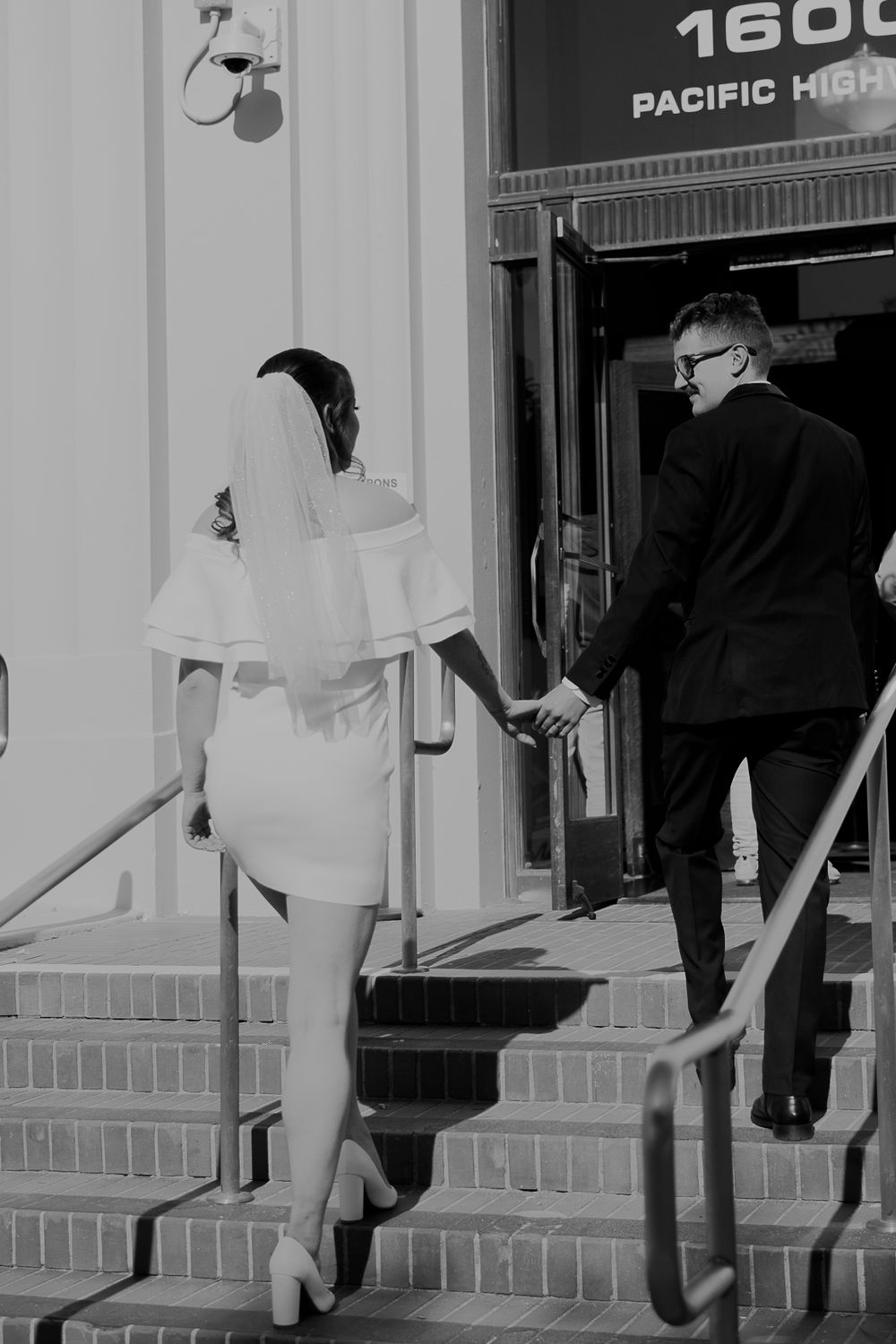 Black and white image of legs and feet walking down concrete steps with shadows visible.
