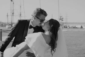 Black and white photo of a couple kissing with palm trees in the background on their wedding day.